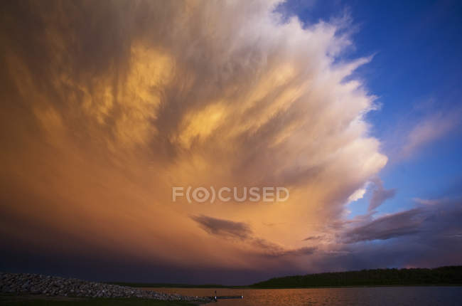 High cloud formation with storm clouds reflecting sunlight over lake in Canada. — Stock Photo