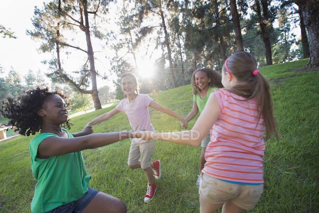 Gruppo di ragazze in età elementare che si tengono per mano e ballano all'aperto . — Foto stock