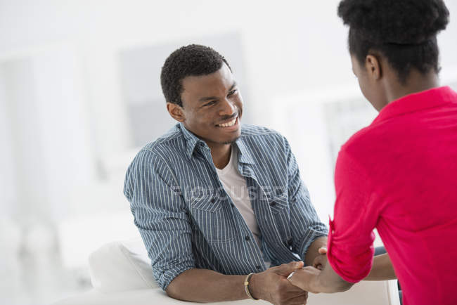 Man and woman talking face to face and holding hands indoors. — Stock Photo