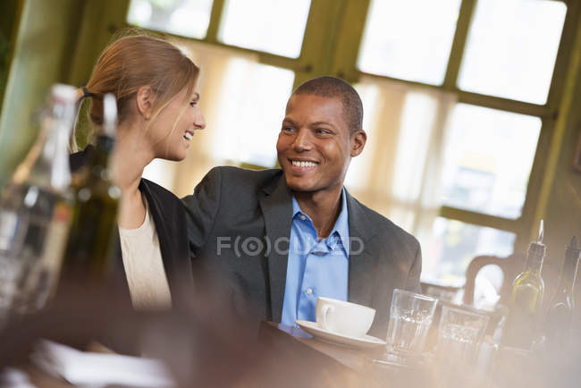 Uomo d'affari e donna d'affari seduti in caffetteria fianco a fianco . — Foto stock