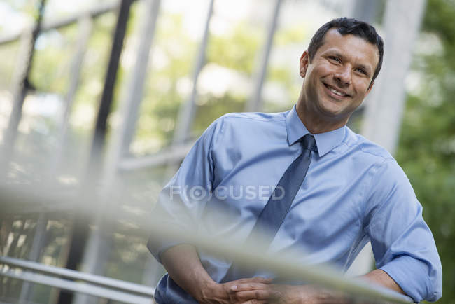 Mitte erwachsener Geschäftsmann in Hemd und Krawatte, an Geländer gelehnt und entspannt. — Stockfoto