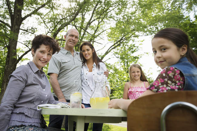 Сім'я збирається за садовим столом і робить свіжий лимонад . — стокове фото