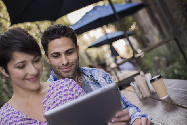 Couple sitting at city cafe and sharing digital tablet. — Stock Photo