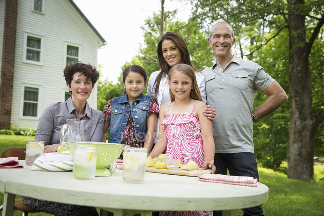 Сім'я збирається за садовим столом і робить свіжий лимонад . — стокове фото
