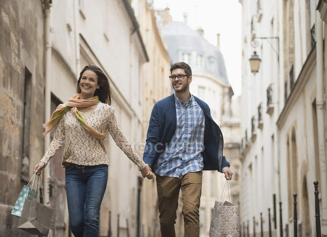 Paar spaziert mit Einkaufstüten durch enge Straße in historischer Stadt. — Stockfoto