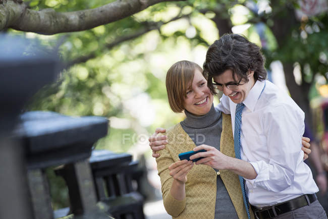 Взрослые мужчины и женщины делятся смартфонами на городской улице . — стоковое фото