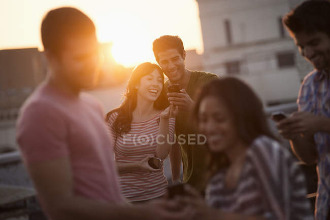 Молоді друзі діляться смартфонами на терасі на даху . — стокове фото