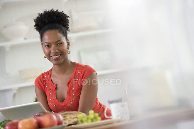 Mid adult woman in holding digital tablet and having cup of coffee at breakfast table. — Stock Photo
