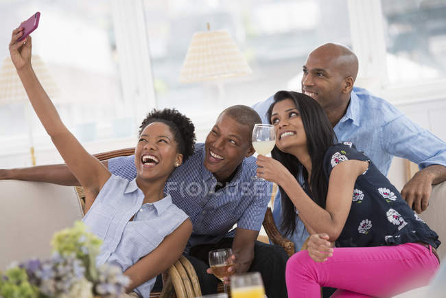 Femme gaie prenant selfie avec des amis avec smartphone à la fête . — Photo de stock