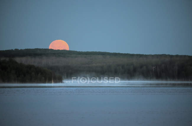 Красная луна над лесом и озером в Канаде — стоковое фото