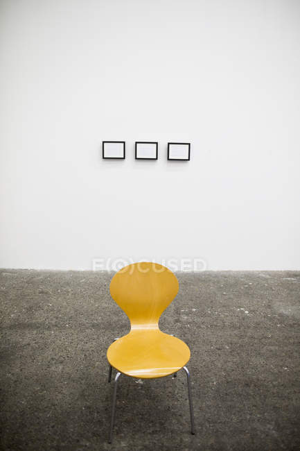 Желтый стул и рамы на белой стене в художественной студии . — стоковое фото