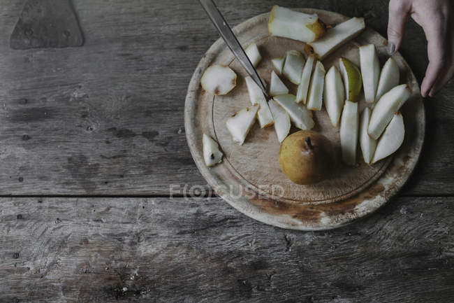 Female hand slicing fresh pears on chopping board. — Stock Photo