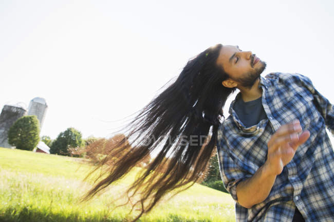 Giovane uomo con lunghi capelli scuri scuotendo la testa e ventilando sull'aria fresca . — Foto stock