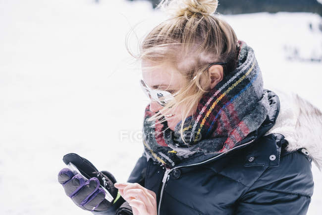 Mulher em roupas de inverno na pista de esqui usando smartphone . — Fotografia de Stock