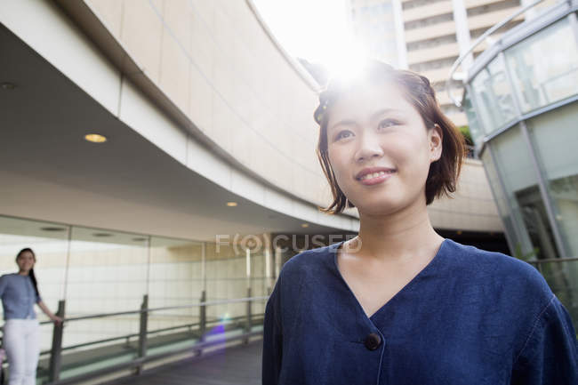 Junge Frau spaziert mit weichem Gegenlicht im Innenhof eines Bürogebäudes. — Stockfoto