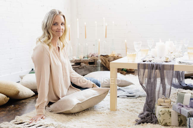 Femme blonde assise à côté du serveur de table pour le repas de célébration avec des bougies et des verres de vin . — Photo de stock