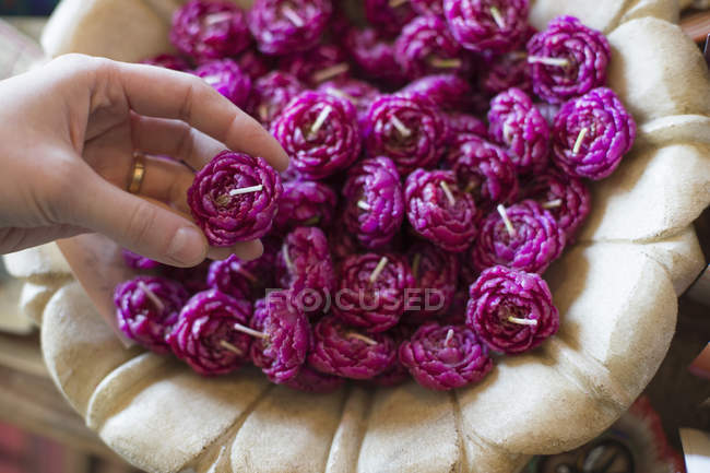 Female hand selecting candle from basket full of purple wax shaped candles. — Stock Photo