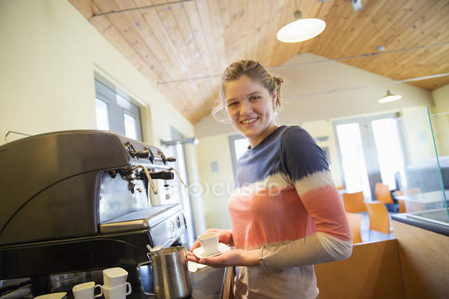 Молода жінка робить каву з використанням великої кавової машини . — стокове фото