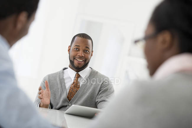 Homem adulto médio com tablet digital sentado em reunião com casal . — Fotografia de Stock