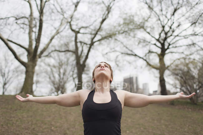 Frau im Central Park macht Yoga mit ausgestreckten Armen. — Stockfoto