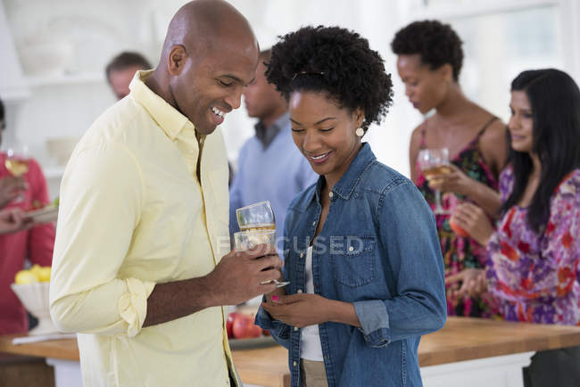 Uomo e donna che tengono bicchieri di vino alla festa con persone in background . — Foto stock