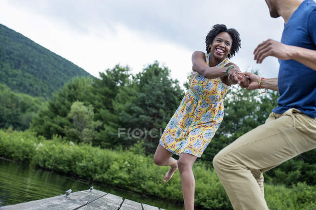 Casal puxando as mãos em molhe de madeira por lago país
. — Fotografia de Stock