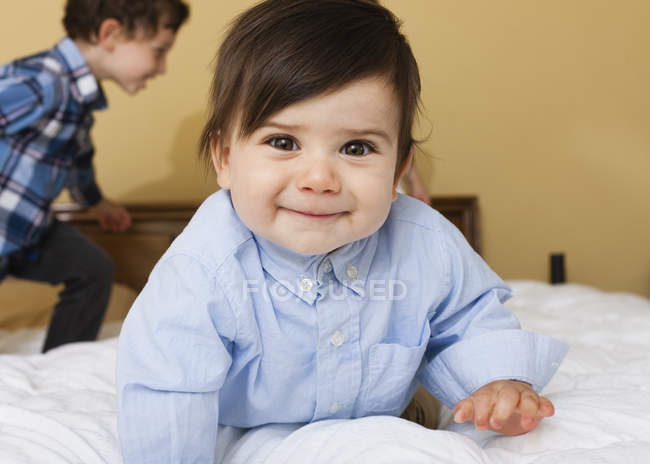 Two children looking in camera while playing on bed. — Stock Photo