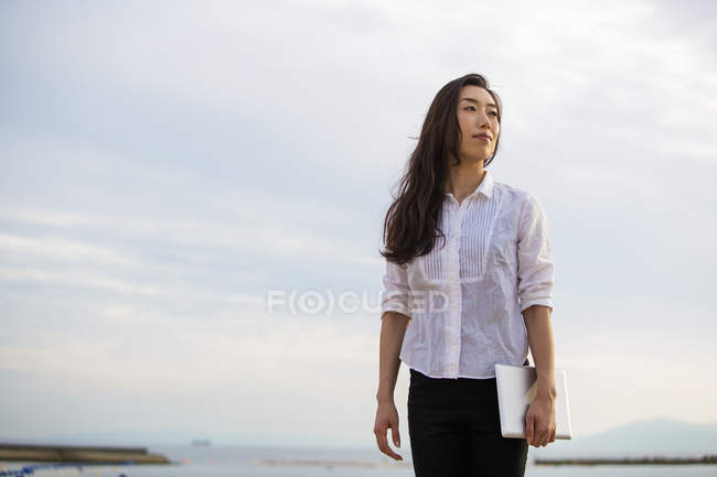 Жінка тримає цифровий планшет і насолоджується погодою на пляжі . — стокове фото