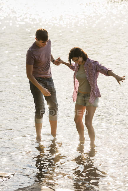 Couple tenant la main en pagayant en eau peu profonde au lac . — Photo de stock