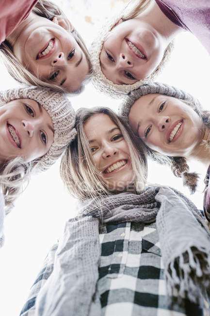 Five teenage girls in woolly hats and scarves looking down in camera outdoors. — Stock Photo