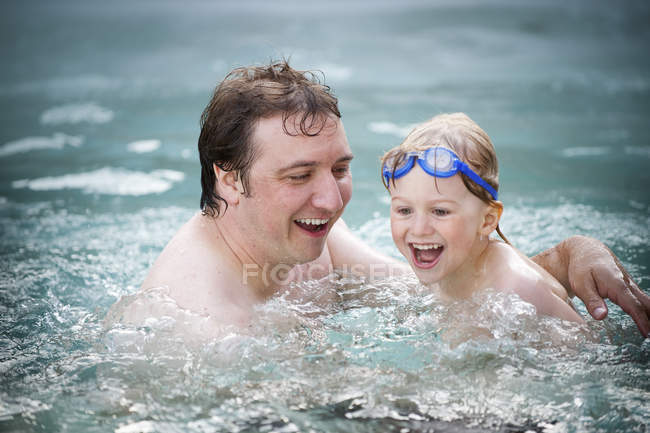 Padre e hijo riendo en el agua de la piscina . - foto de stock
