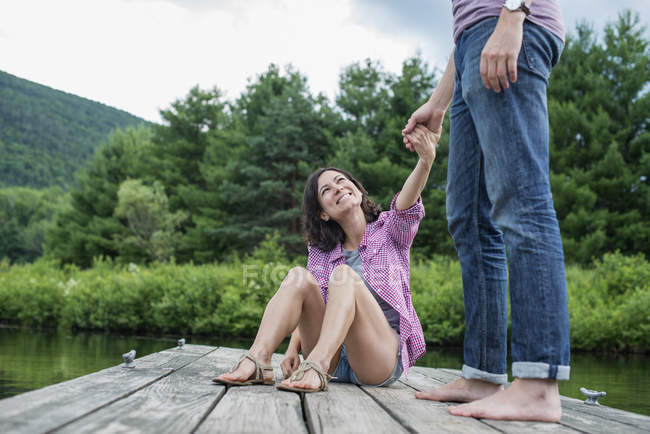 Пара держащихся за руки на деревянном причале у озера . — стоковое фото