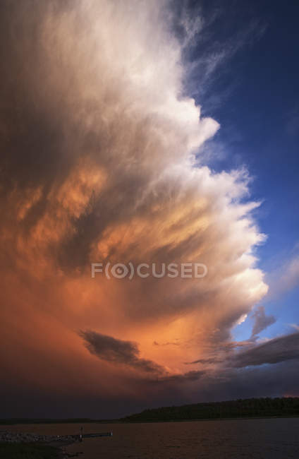 Hohe Wolkenbildung mit Gewitterwolken, die das Sonnenlicht über dem See in Kanada reflektieren. — Stockfoto