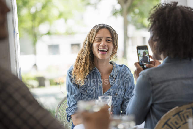 Женщина говорит фото друга со смартфоном в интерьере кофейни . — стоковое фото
