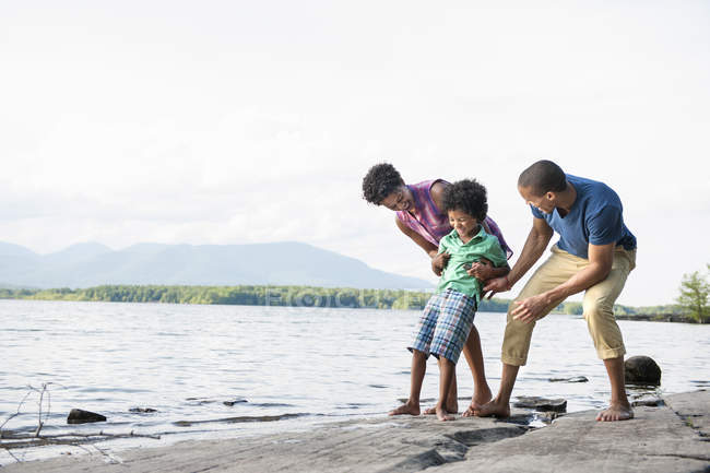 Famille avec fils jouant sur la rive du lac dans les bois . — Photo de stock