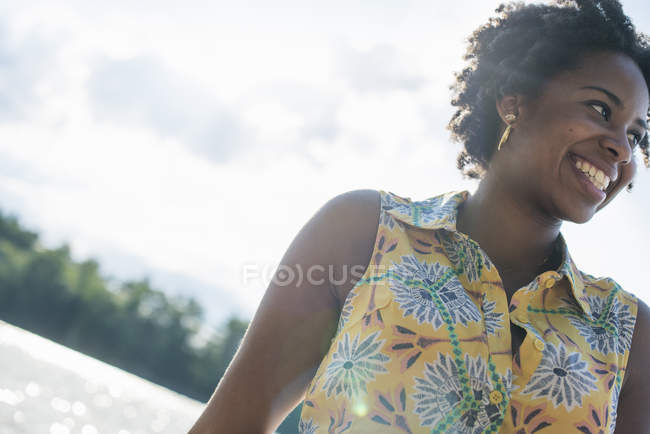 Низкий угол обзора женщины, улыбающейся на берегу озера . — стоковое фото