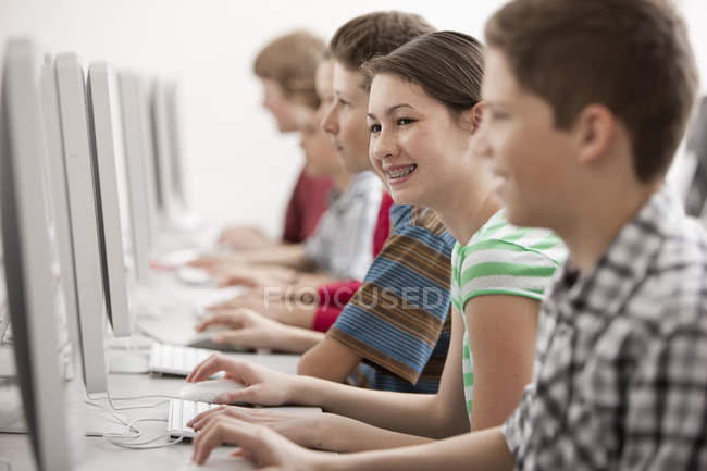Group of boys and girl in computer class working at monitors. — Stock Photo