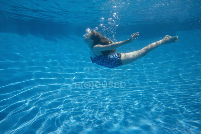 Допідліток дівчина з плаванням довге волосся плаває під водою в басейні . — стокове фото