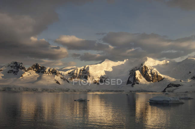 Dusk and flat calm water of shore of mountain landscape in Antarctica. — Stock Photo