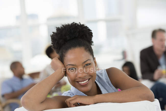 Mid adult woman smiling and looking in camera with people having party in background. — Stock Photo