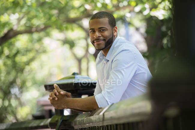 Young man in white shirt leaning on railing in city. — Stock Photo