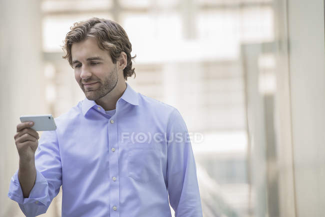 Mann in Hemd und Krawatte mit Smartphone in Großstadtszene. — Stockfoto