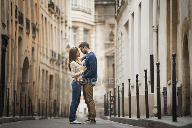 Взрослая пара, стоящая и смотрящая друг на друга на узкой улице в городе . — стоковое фото