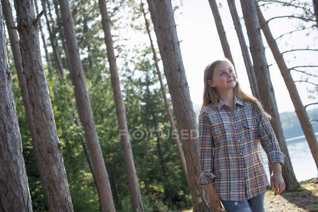 Menina pré-adolescente andando na floresta ao lado do lago no verão . — Fotografia de Stock