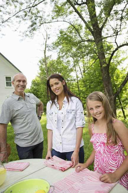 Father and daughters standing by garden table. — Stock Photo