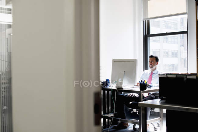 Maduro homem sentado no escritório e usando computador . — Fotografia de Stock
