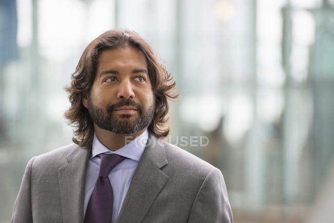 Hispânico maduro homem no terno jaqueta e roxo gravata olhando para longe na cidade . — Fotografia de Stock