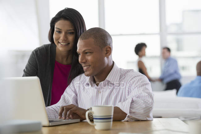 Giovane uomo e donna che condividono computer portatile in ufficio sul posto di lavoro . — Foto stock