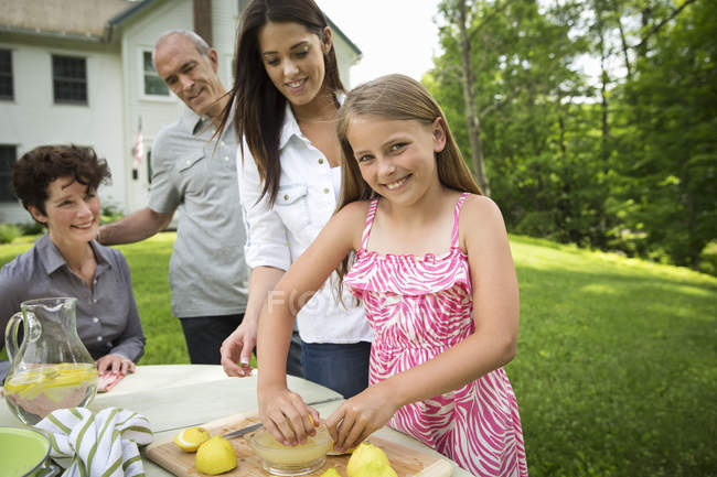 Famiglia che si riunisce al tavolo da giardino e fa limonata fresca . — Foto stock