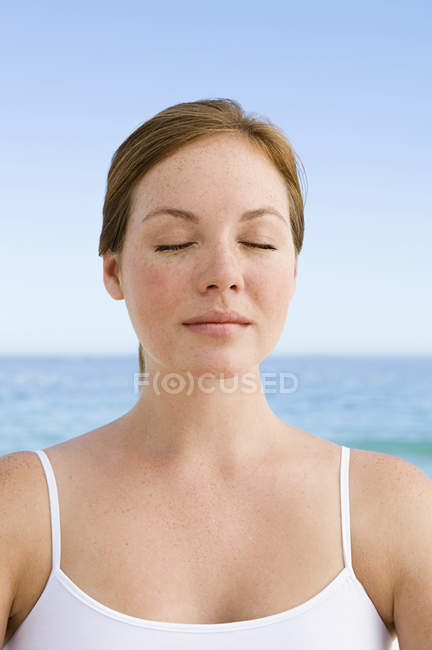 Young woman on beach in relaxed pose with eyes closed. — Stock Photo